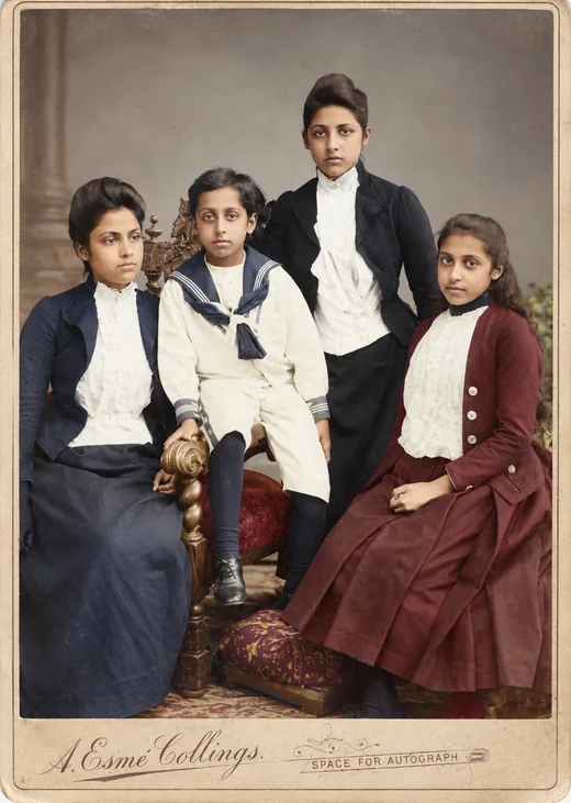 Studio photograph of four of Duleep Singh's children: three young women in dark jackets and high-necked white blouses, and a boy in a sailor suit seated on a carved chair