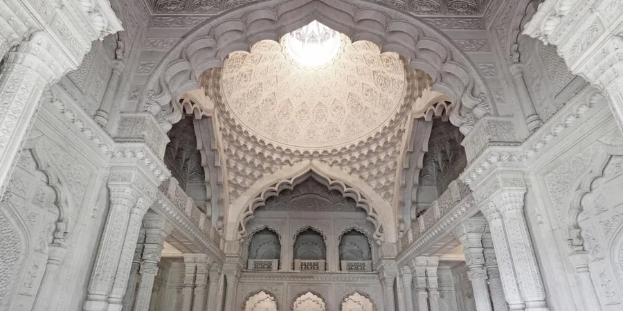 The domed central hall at Elveden: white carved plaster arches, columns and a shallow ribbed dome pierced by a lantern, in a Mughal idiom